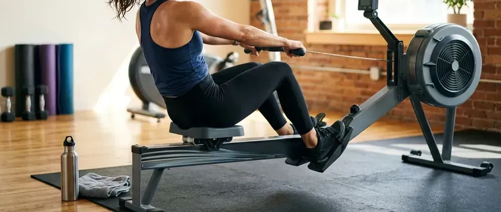Person doing an interval on a cardio machine in a bright fitness studio, seen from the side